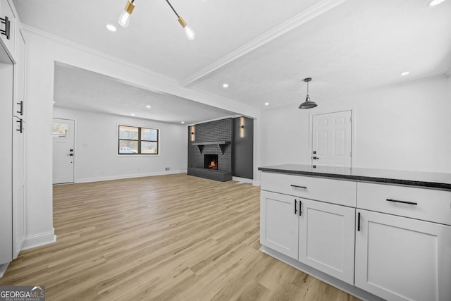 interior space with ornamental molding, light wood finished floors, a brick fireplace, and recessed lighting