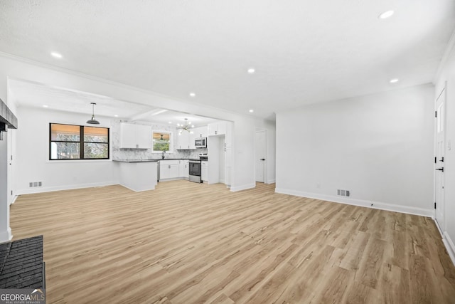 unfurnished living room featuring light wood finished floors, baseboards, a sink, and recessed lighting