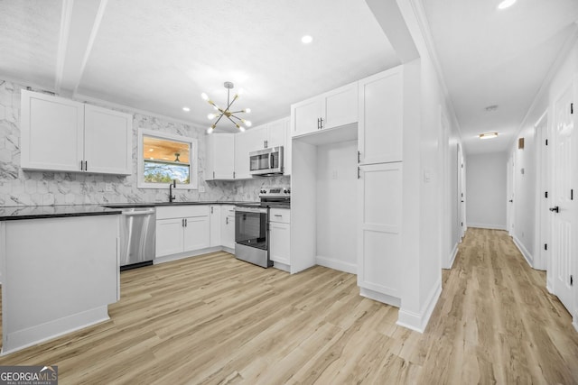 kitchen featuring appliances with stainless steel finishes, dark countertops, a sink, and white cabinets