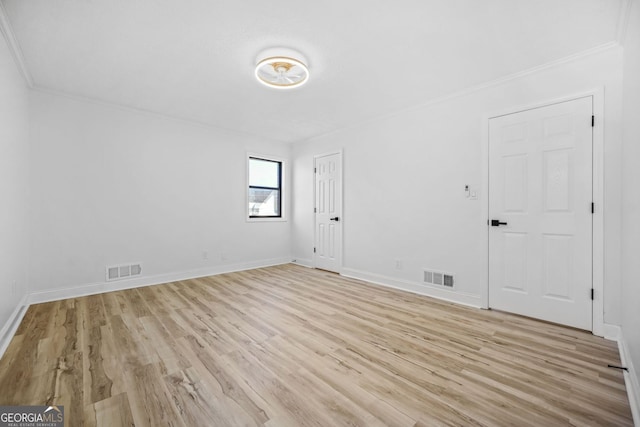 spare room featuring light wood finished floors, visible vents, and baseboards