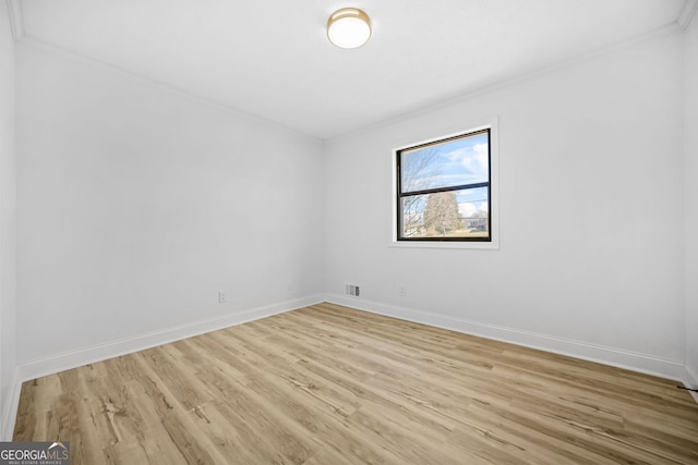 spare room with baseboards, ornamental molding, visible vents, and light wood-style floors