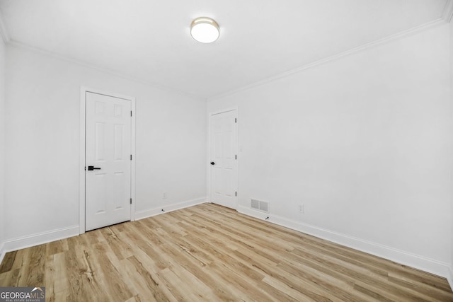 spare room featuring crown molding, light wood-style flooring, visible vents, and baseboards