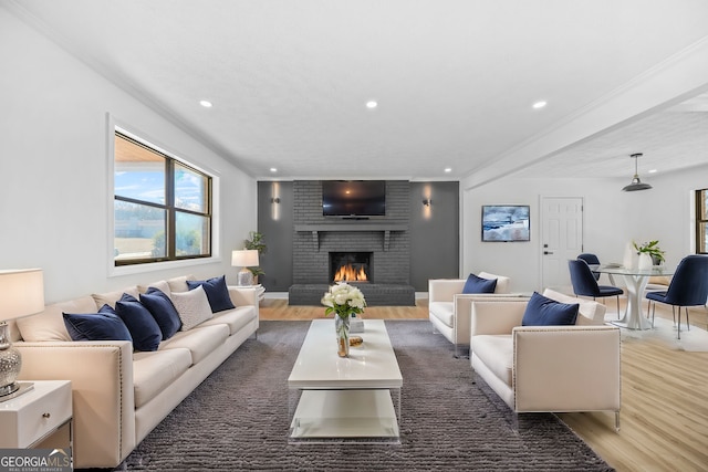 living area featuring recessed lighting, a fireplace, wood finished floors, baseboards, and crown molding