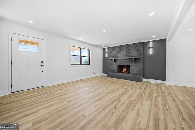 unfurnished living room with light wood-type flooring, a brick fireplace, baseboards, and recessed lighting