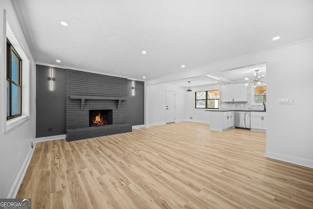 unfurnished living room featuring baseboards, crown molding, light wood-type flooring, a brick fireplace, and recessed lighting