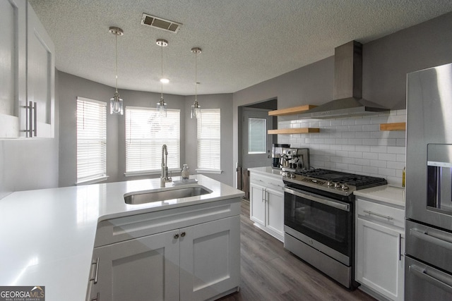 kitchen with a sink, visible vents, light countertops, appliances with stainless steel finishes, and wall chimney exhaust hood