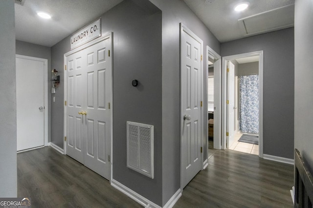 hall with dark wood-style floors, visible vents, and baseboards