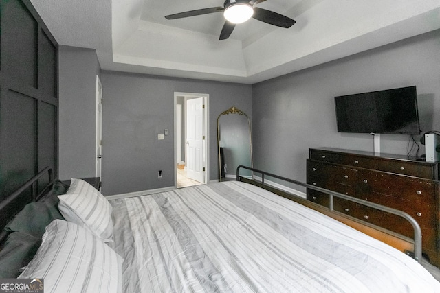 bedroom featuring ceiling fan, a tray ceiling, and wood finished floors