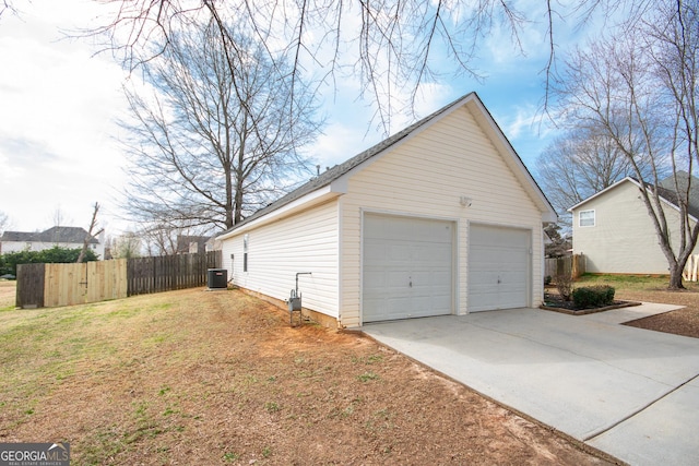 view of side of property featuring a detached garage, fence, central AC, and an outbuilding