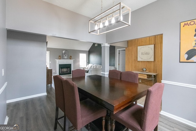 dining area with a fireplace, wood finished floors, decorative columns, and baseboards