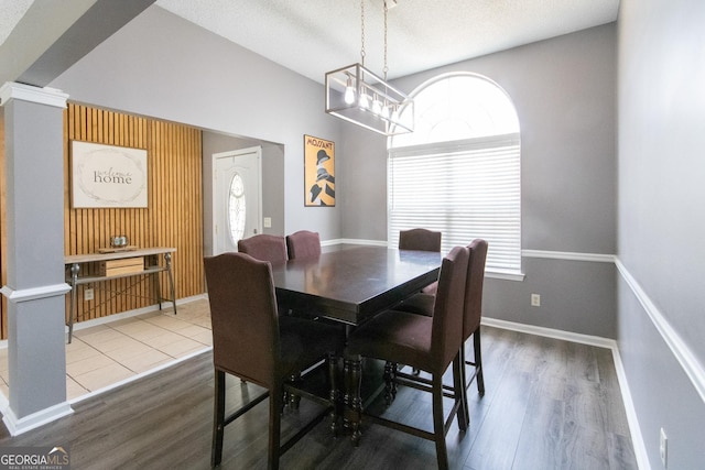 dining area featuring baseboards, wood finished floors, and ornate columns