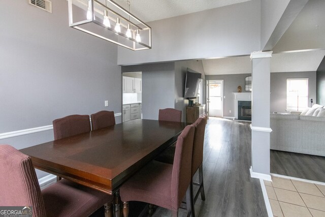 dining space featuring decorative columns, visible vents, baseboards, light wood-type flooring, and a fireplace