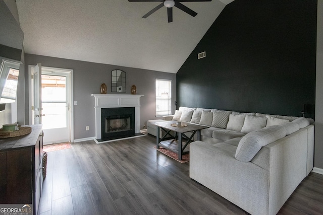 living area featuring ceiling fan, dark wood-style flooring, visible vents, baseboards, and a glass covered fireplace