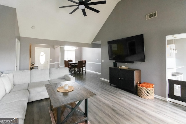 living area with visible vents, ceiling fan, wood finished floors, high vaulted ceiling, and baseboards