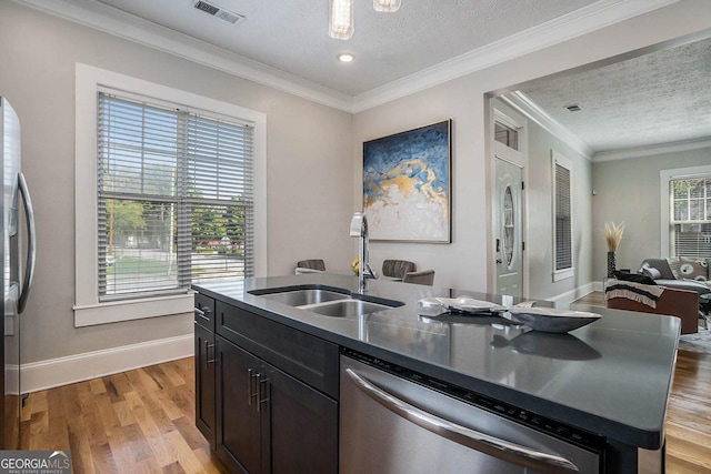 kitchen with visible vents, light wood finished floors, a sink, stainless steel appliances, and crown molding