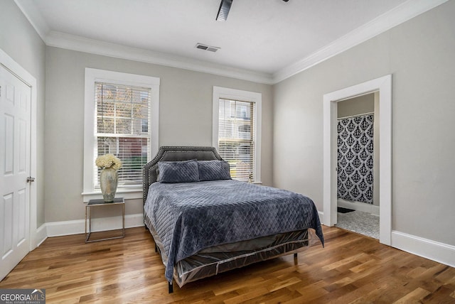 bedroom with visible vents, wood finished floors, baseboards, and ornamental molding