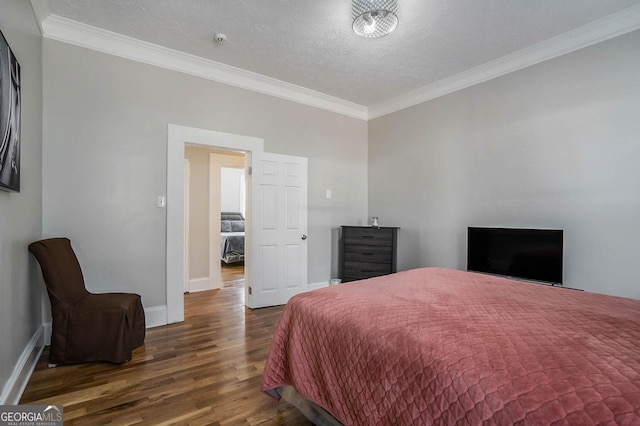 bedroom featuring ornamental molding, a textured ceiling, baseboards, and wood finished floors