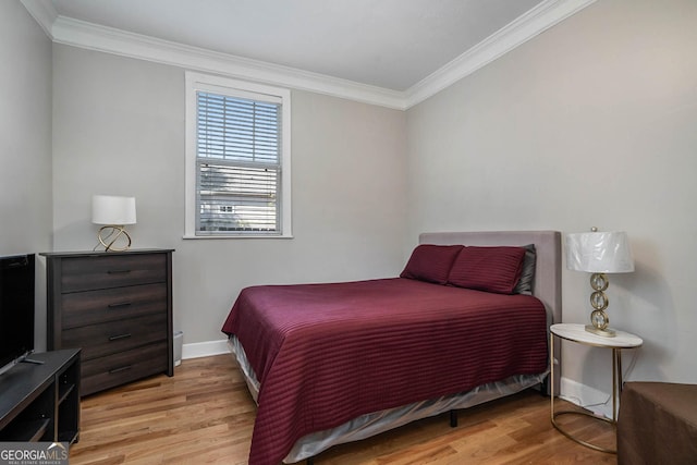 bedroom with light wood-type flooring, baseboards, and crown molding