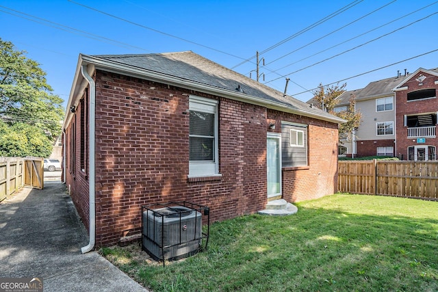 rear view of property with brick siding, central AC unit, and fence