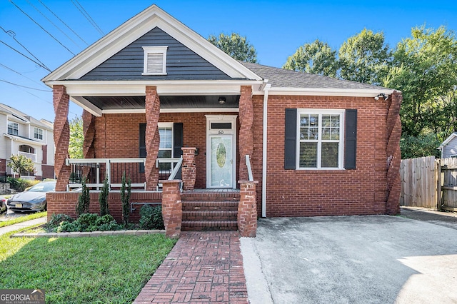 view of front facade with a porch, fence, and brick siding