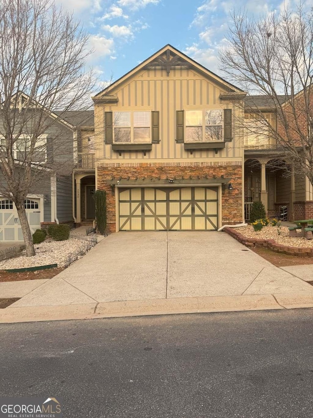 view of front of home with a balcony, a garage, brick siding, concrete driveway, and board and batten siding