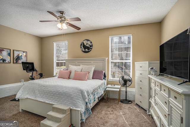 carpeted bedroom featuring a textured ceiling, multiple windows, a ceiling fan, and baseboards