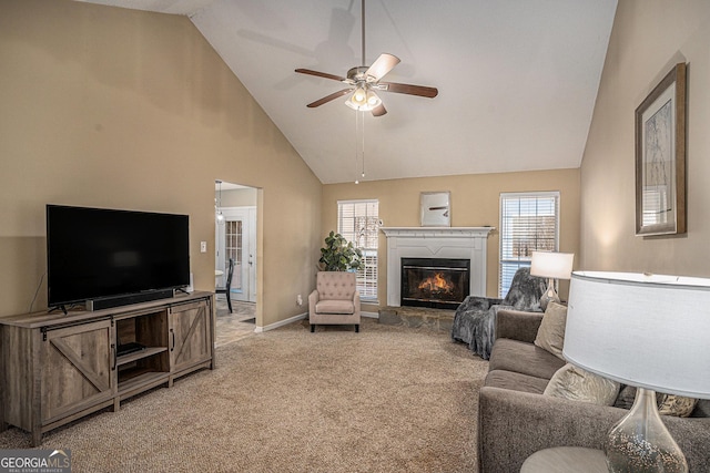 living area with light carpet, a ceiling fan, a wealth of natural light, and a glass covered fireplace