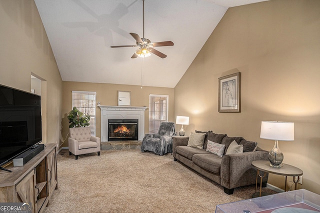 living area with ceiling fan, a healthy amount of sunlight, a glass covered fireplace, and light colored carpet