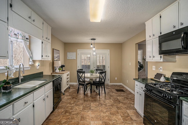 kitchen with black appliances, dark countertops, a sink, and white cabinets