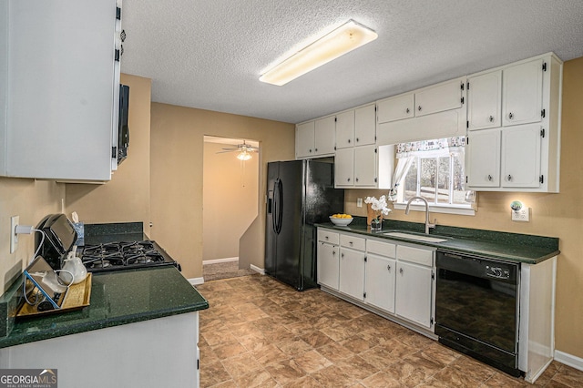 kitchen featuring baseboards, dark countertops, black appliances, white cabinetry, and a sink