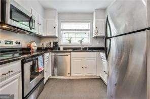 kitchen featuring stainless steel appliances, dark countertops, white cabinets, and a sink