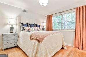 bedroom with baseboards, visible vents, and wood finished floors