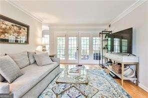 living area with baseboards, french doors, wood finished floors, and crown molding