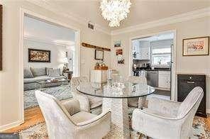 dining room with an inviting chandelier, baseboards, crown molding, and wood finished floors