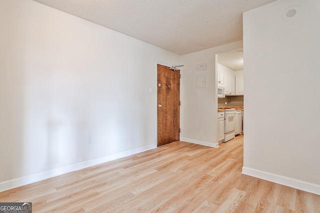 unfurnished living room featuring light wood-style floors, baseboards, and a textured ceiling