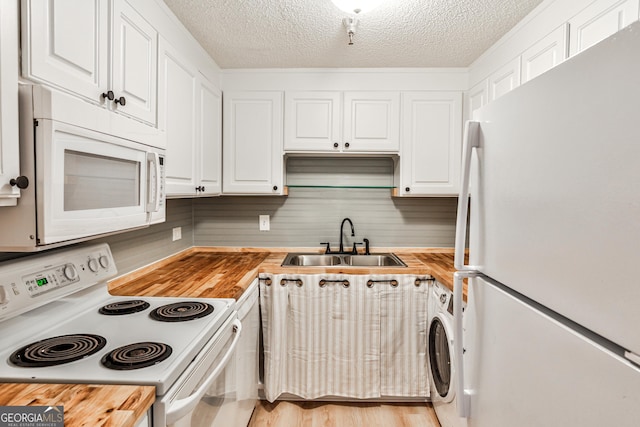 kitchen featuring butcher block counters, white cabinets, a sink, washer / dryer, and white appliances