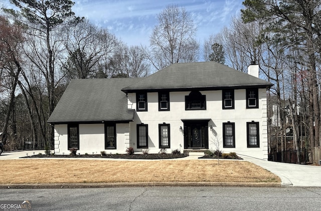 view of front of home featuring stucco siding, roof with shingles, and a chimney