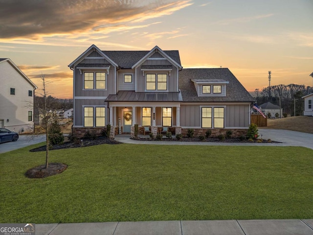 craftsman house featuring a shingled roof, stone siding, covered porch, a front lawn, and board and batten siding