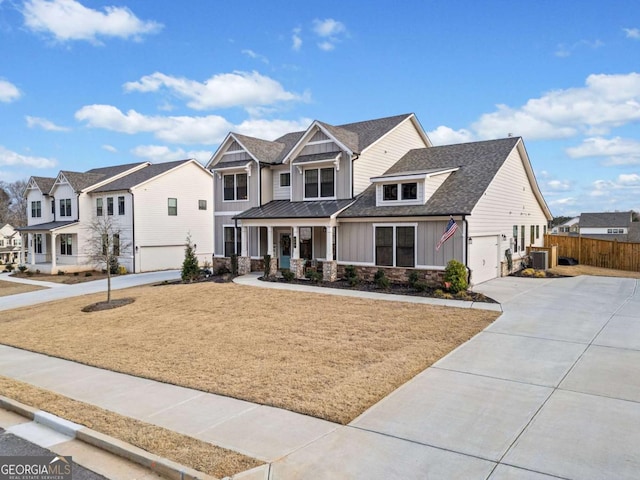 view of front of property featuring a garage, fence, concrete driveway, a residential view, and board and batten siding