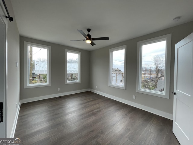 unfurnished room featuring dark wood-style floors, ceiling fan, visible vents, and baseboards