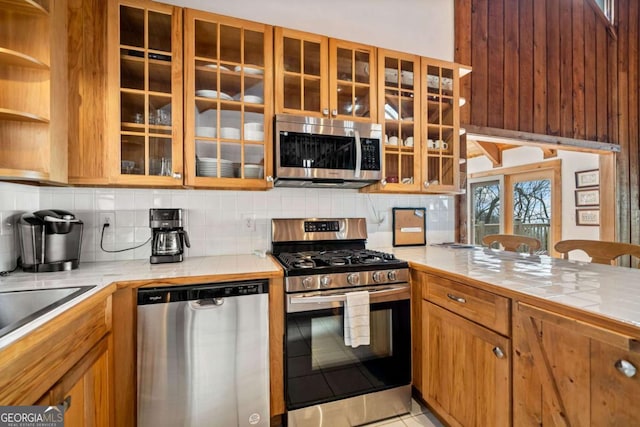 kitchen featuring tasteful backsplash, appliances with stainless steel finishes, brown cabinets, and tile counters