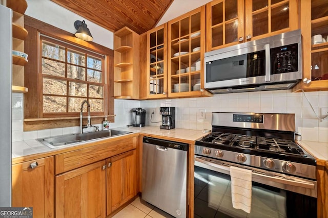 kitchen with tile countertops, stainless steel appliances, a sink, decorative backsplash, and open shelves