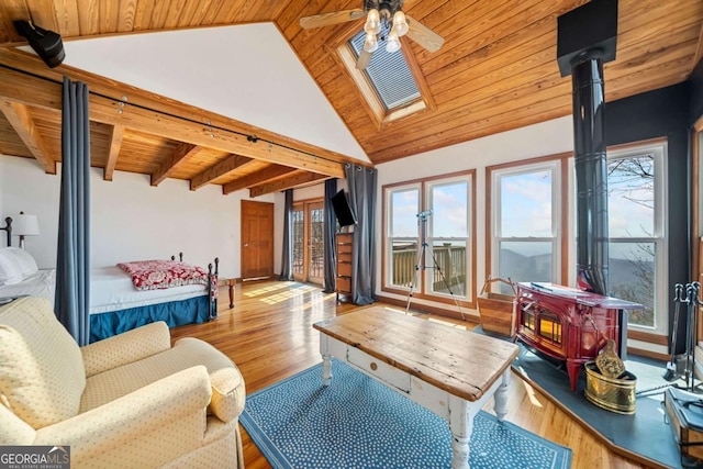 sunroom with wood ceiling, lofted ceiling with beams, a wood stove, and a ceiling fan