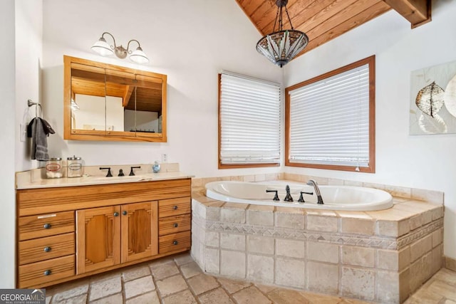 full bath featuring a garden tub, vanity, wood ceiling, vaulted ceiling, and stone tile flooring