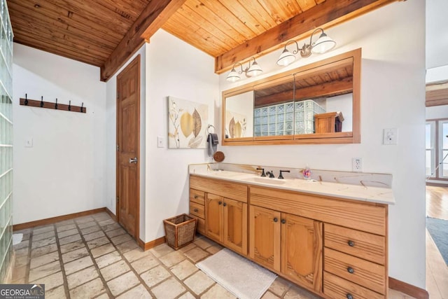 bathroom featuring beam ceiling, stone tile flooring, vanity, wooden ceiling, and baseboards