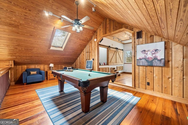 recreation room with lofted ceiling, a barn door, wooden walls, wood ceiling, and hardwood / wood-style floors