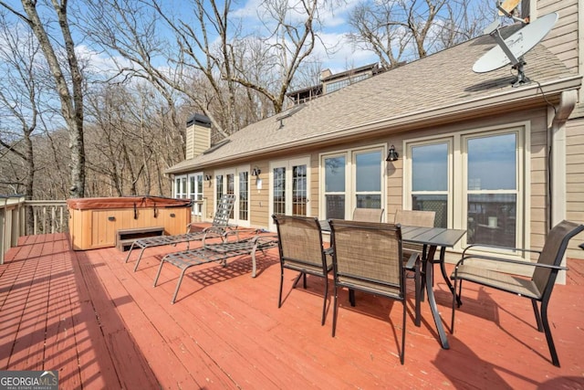 deck with a hot tub and outdoor dining space