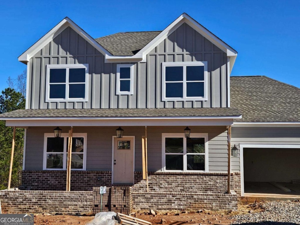 view of front of home with covered porch, board and batten siding, and brick siding