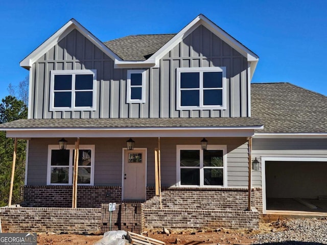 view of front of home with covered porch, board and batten siding, and brick siding