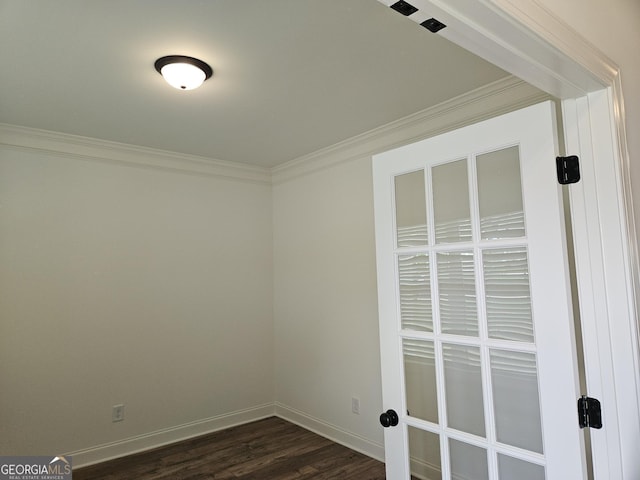 empty room featuring crown molding, baseboards, and dark wood-type flooring